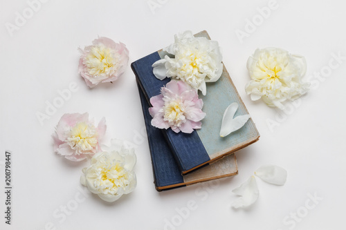 White and pink peonies and old books on white background