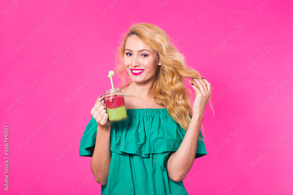 Young beautiful woman with green smoothie on pink background Young beautiful woman with green smoothie on pink background