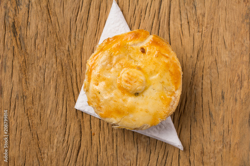 Stuffed chicken pie known as Empada in Portugal and Brazil. One snack on rustic wood table, top view. photo