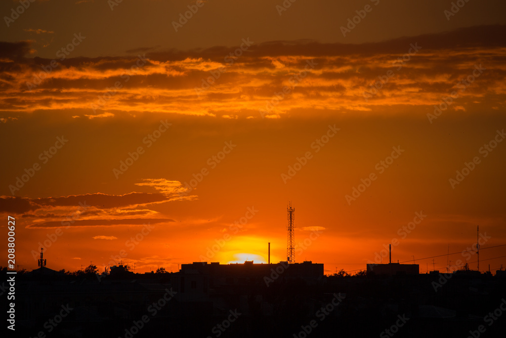 Sunset in the city with cellular tower and clouds