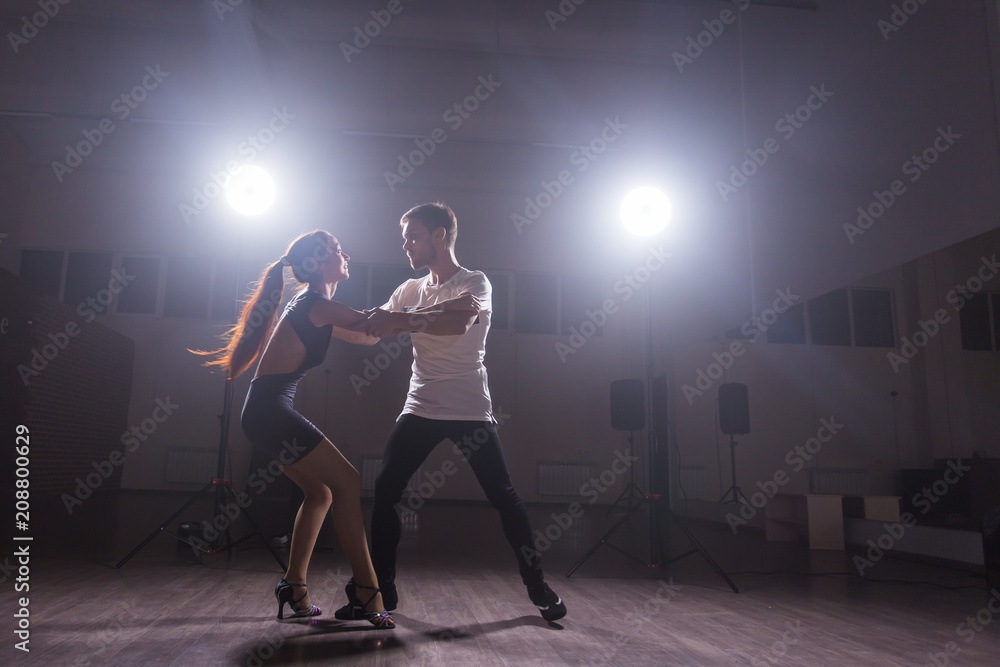 Skillful dancers performing in the dark room under the concert light and smoke. Sensual couple performing an artistic and emotional contemporary dance Skillful dancers performing in the dark room under the concert light and smoke. Sensual couple performing an artistic and emotional contemporary dance