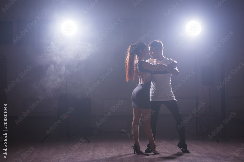 Skillful dancers performing in the dark room under the concert light and smoke. Sensual couple performing an artistic and emotional contemporary dance