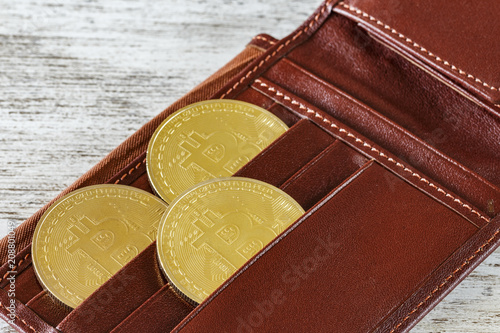 Metal bitcoins in brown leather wallet. Bitcoin - modern virtual coins. Block chain technology