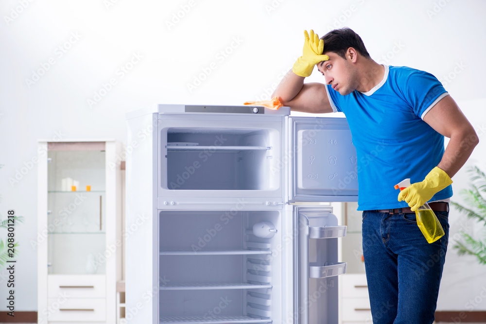 Man cleaning fridge in hygiene concept Man cleaning fridge in hygiene concept