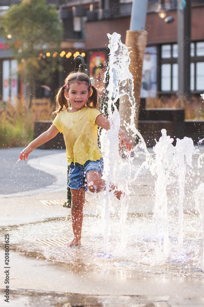 Cute little girl playing with water in fountain on the street in La Mer ...