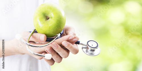 hands with Apple and stethoscope, healthy eating concept