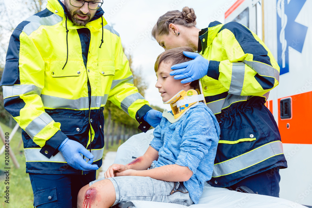 Rettungssanitäter versorgen einen verletzten Jungen Rettungssanitäter versorgen einen verletzten Jungen
