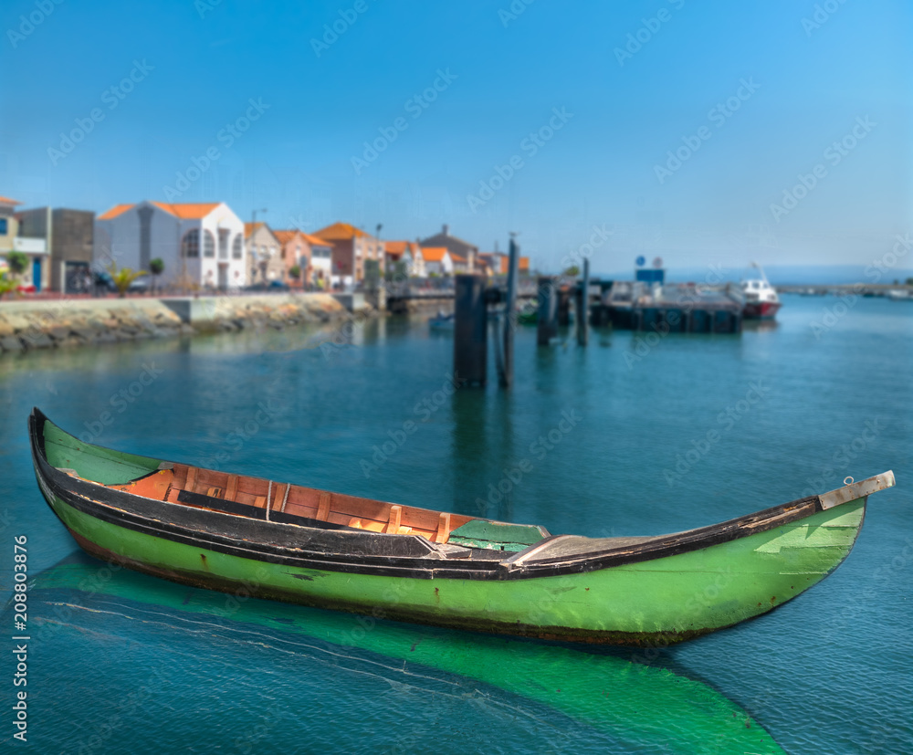 On the calm water of the bay sits a green gondola.