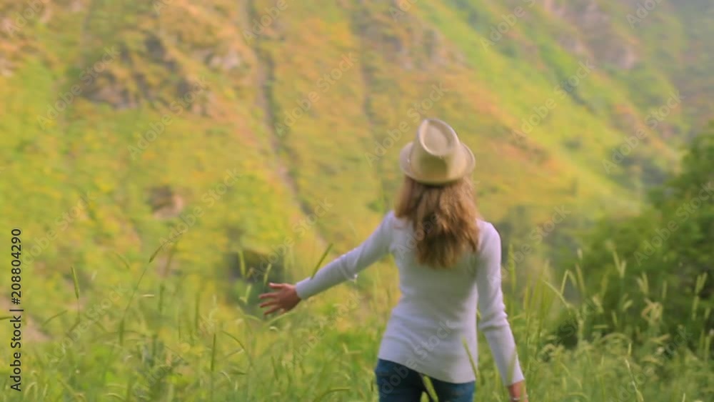 Girl walking on a hillside with wheat. Scenic view. Smooth motion of the camera Girl walking on a hillside with wheat. Scenic view. Smooth motion of the camera