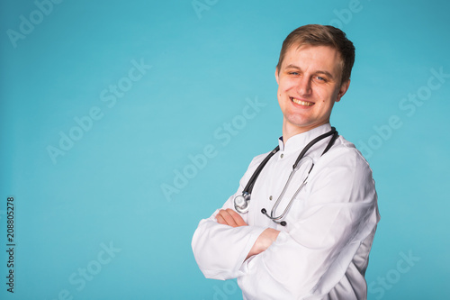 Smiling medical doctor man with stethoscope over blue background with copy space