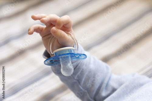 Child's hand holding a pacifier, close-up