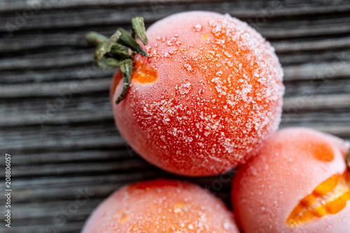 frozen cherry tomatoes on wood background, top view, macro
