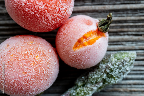 frozen cherry tomatoes and asparagus on wood background, top view, macro