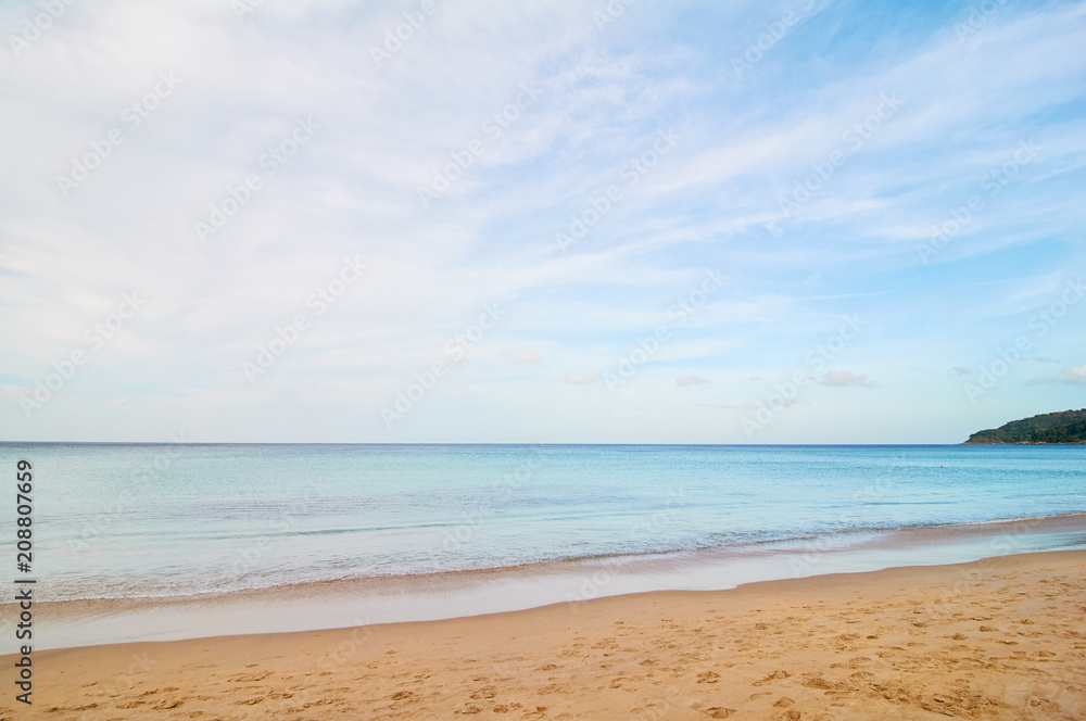 Sand beach with blue water and sky.