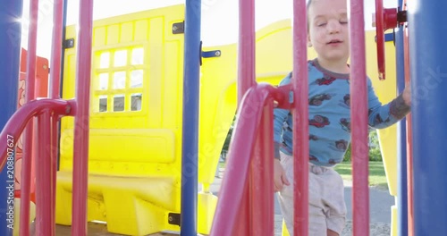 Toddler boy on playstructure in summer sun - slow motion photo