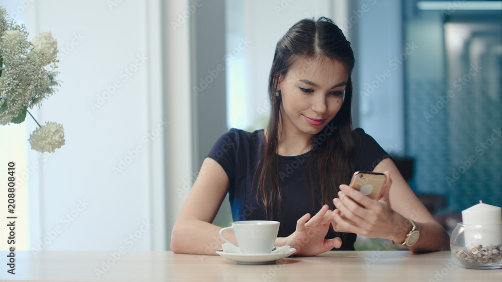 Happy female watching her photos on cell phone in coffee shop Happy female watching her photos on cell phone in coffee shop