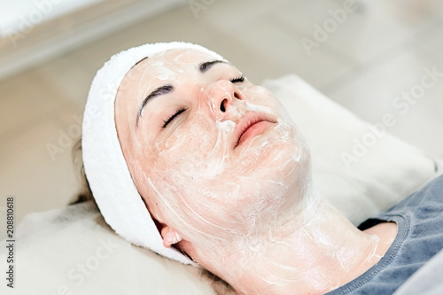 Young woman lying on a couch with a cream applied on her face for lifting