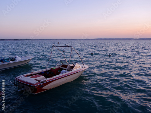 Motorboat floating over turquoise waters of a lake in sunset