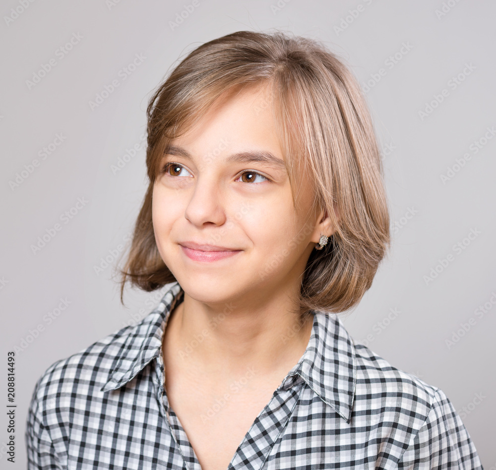 Beautiful caucasian teen girl on gray background. Schoolgirl smiling and looking away. Happy child - emotional portrait close-up. Beautiful caucasian teen girl on gray background. Schoolgirl smiling and looking away. Happy child - emotional portrait close-up.