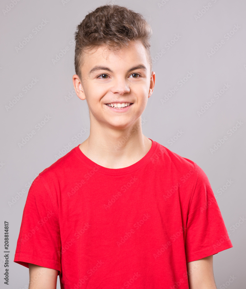 Close up emotional portrait of caucasian teen boy. Handsome smiling guy. Funny cut teenager on gray background. Child looking away. Close up emotional portrait of caucasian teen boy. Handsome smiling guy. Funny cut teenager on gray background. Child looking away.