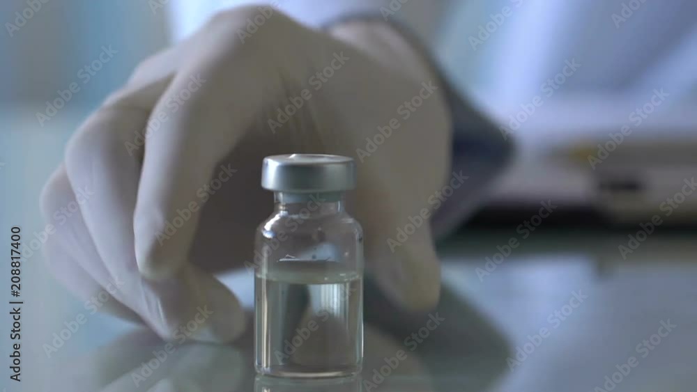 Doctor putting vaccine ampoule on table, prescribing medication, virus epidemic Doctor putting vaccine ampoule on table, prescribing medication, virus epidemic