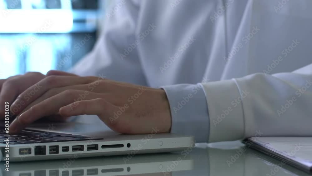 Laboratory researcher working on laptop and filling experiment report documents Laboratory researcher working on laptop and filling experiment report documents