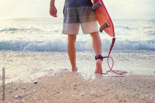 It's surfing time! Hobby and vacation. Close up of surfer's feet on sand beach.
