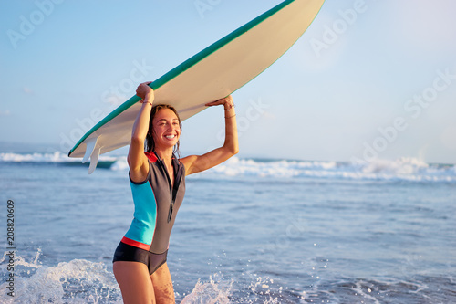 It's time for surfing! Hobby and vacation. Pretty young woman holding surf board on the sea shore.