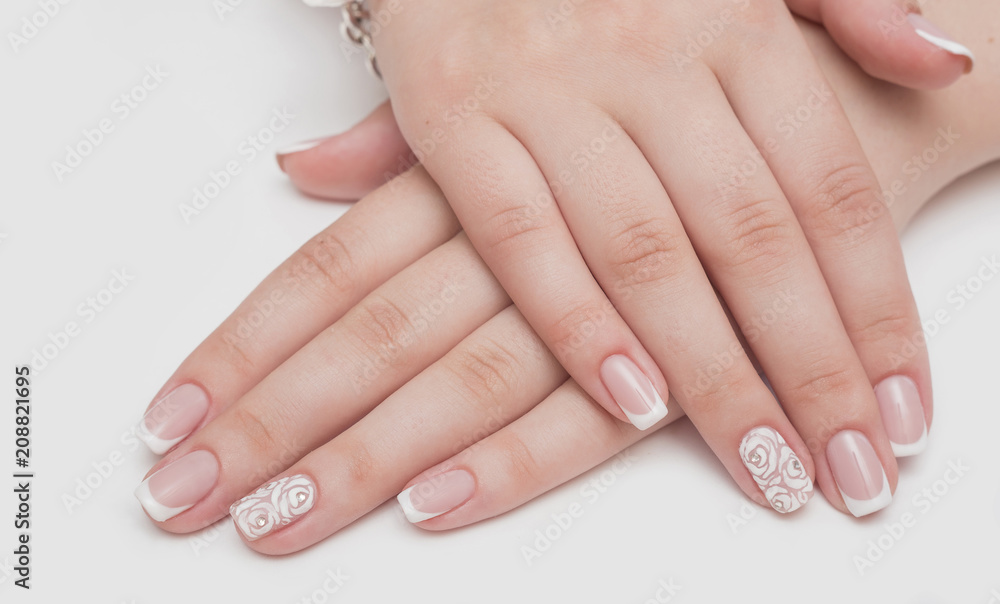 Manicure with rhinestones in the shape of hearts and pink balls on white and red nail Polish on a white background. Manicure with rhinestones in the shape of hearts and pink balls on white and red nail Polish on a white background.