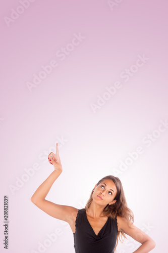 Pretty girl pointing with her hand up. Copy space photo with customizable background.