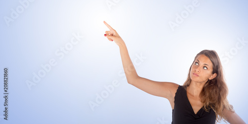 Pretty girl pointing with her hand up. Copy space photo with customizable background.