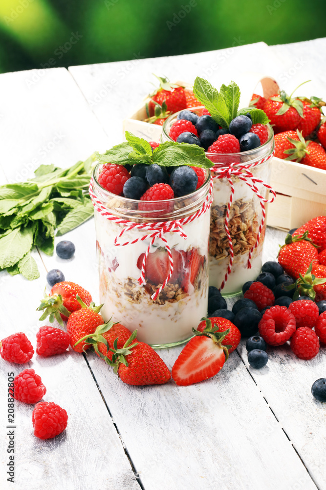 Glass jar of homemade granola with yogurt and fresh berries Glass jar of homemade granola with yogurt and fresh berries