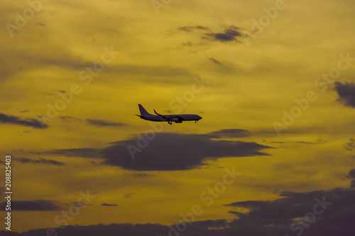 Silhouette of an airplane during landing on sunset background