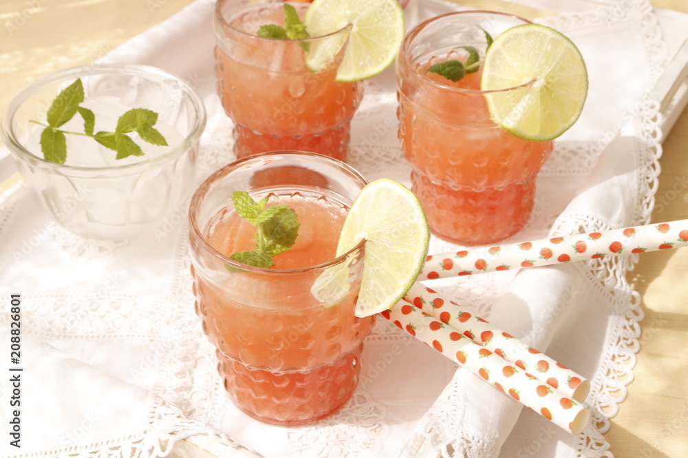 Pink grapefruit juice in glasses with straws.