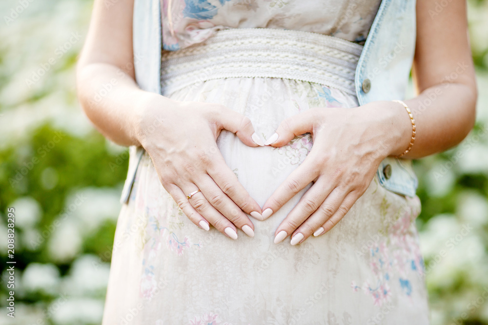 Close-up image of pregnant woman touching her belly with hands Close-up image of pregnant woman touching her belly with hands