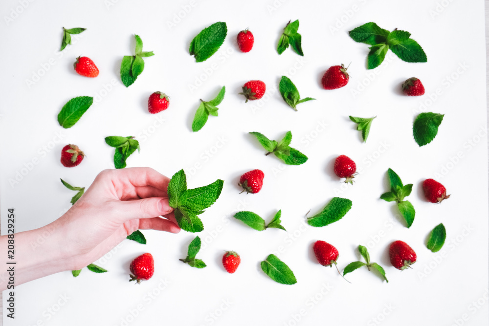 Strawberries and fresh mint on white background with female hand holding mint leaf Strawberries and fresh mint on white background with female hand holding mint leaf
