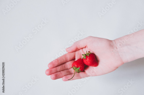 Woman hand holding strawberries on white background, close up