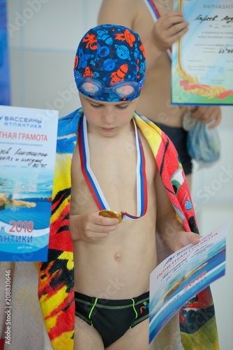 Sad little boy with a medal for swimming
