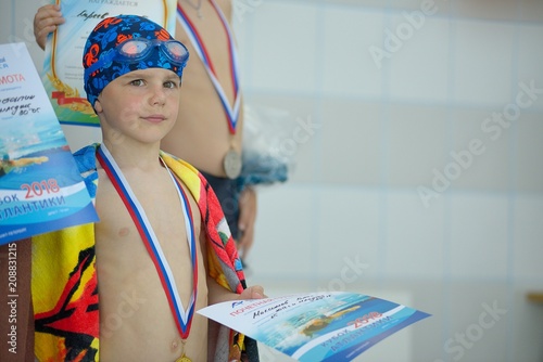 Sad little boy with a medal for swimming photo