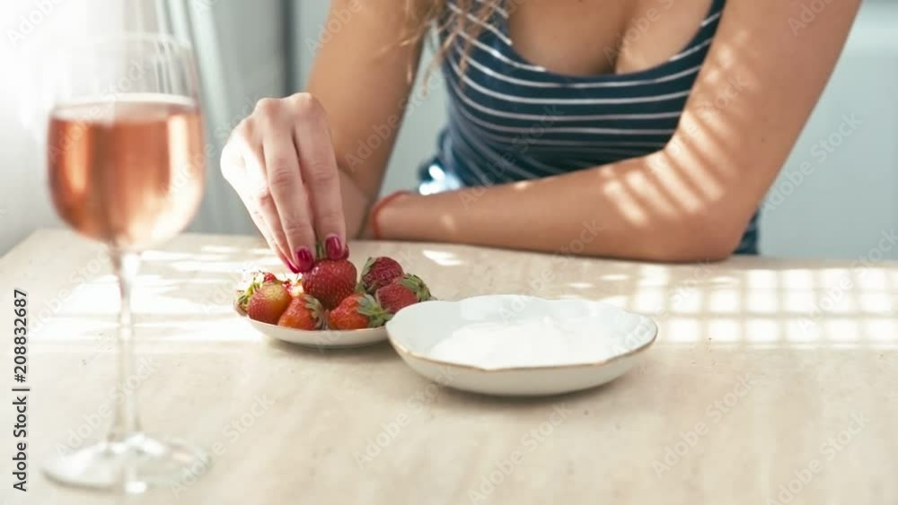 Beautiful young woman eats strawberry with cream, slow motion, tripod shot, shallow depth of field Beautiful young woman eats strawberry with cream, slow motion, tripod shot, shallow depth of field