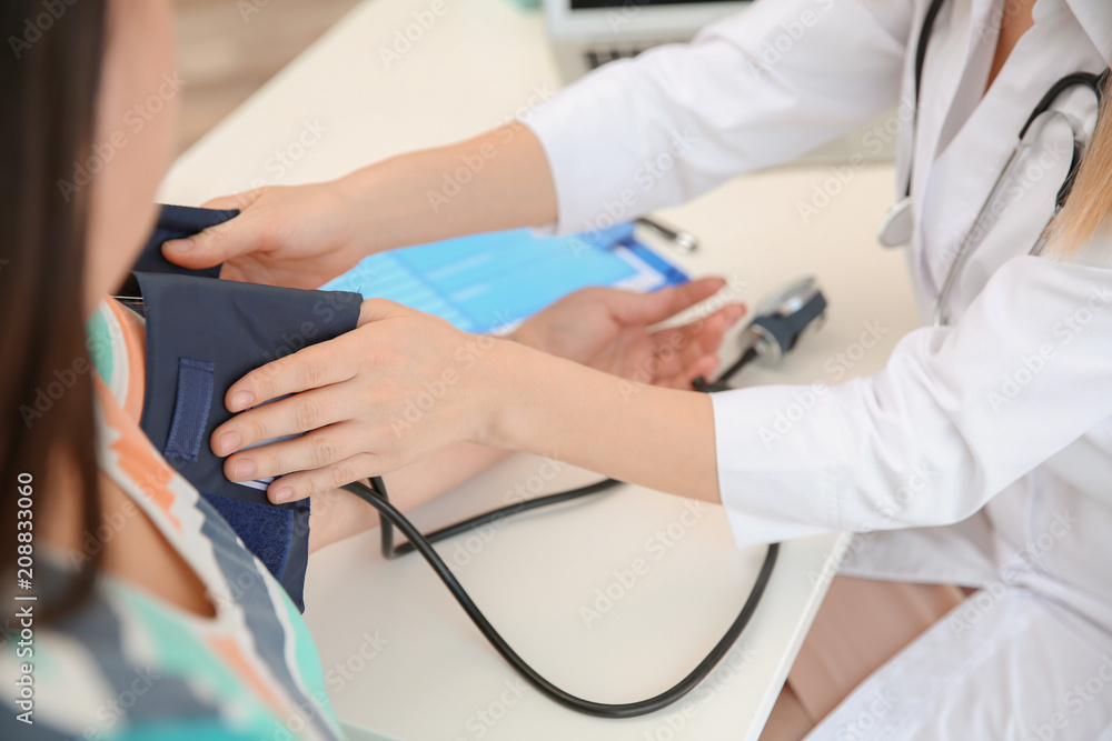 Female doctor measuring blood pressure of overweight woman in clinic Female doctor measuring blood pressure of overweight woman in clinic