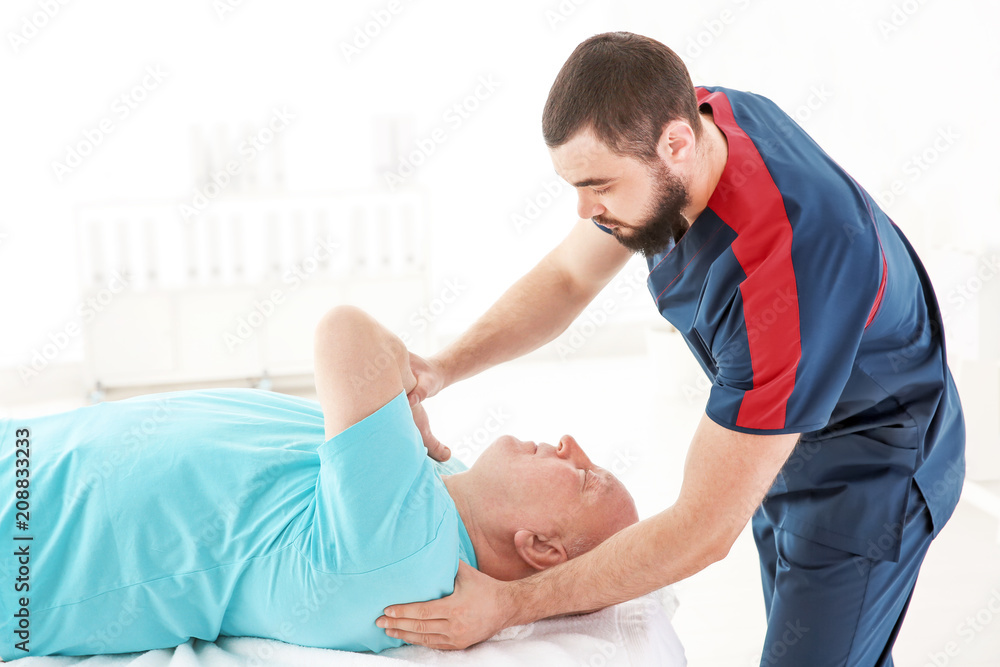 Obraz premium Young physiotherapist working with senior patient in clinic