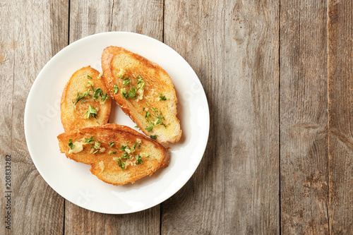 Plate with delicious homemade garlic bread on wooden background
