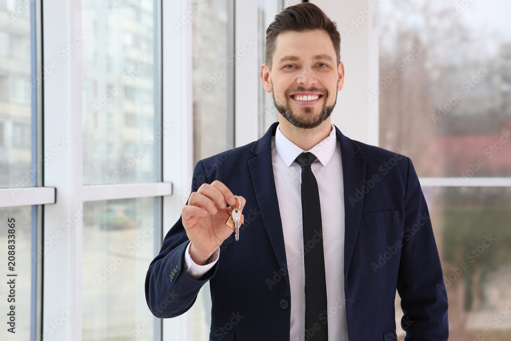 Real estate agent holding house key, indoors Real estate agent holding house key, indoors