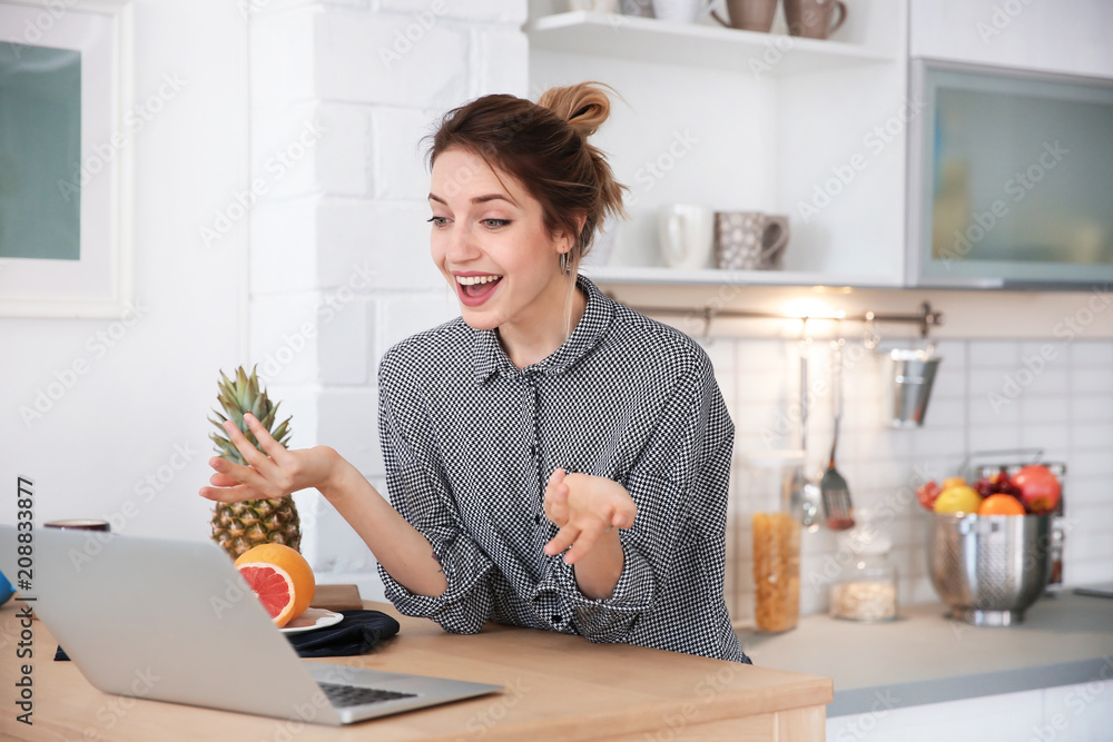 Young blogger with fruits and laptop on kitchen Young blogger with fruits and laptop on kitchen