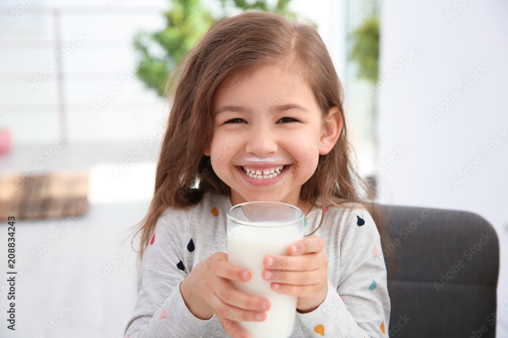 Cute little girl with glass of milk indoors - obrazy, fototapety, plakaty 