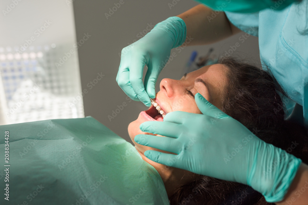 Dentist fixing dental braces to female patient Dentist fixing dental braces to female patient