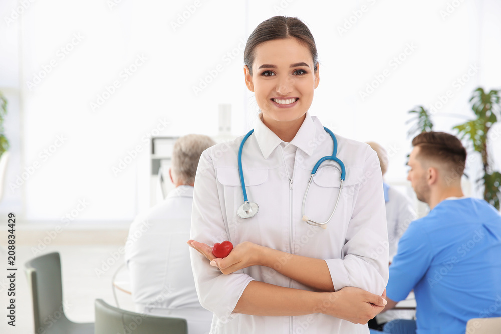 Female doctor holding small heart in clinic. Cardiology center Female doctor holding small heart in clinic. Cardiology center