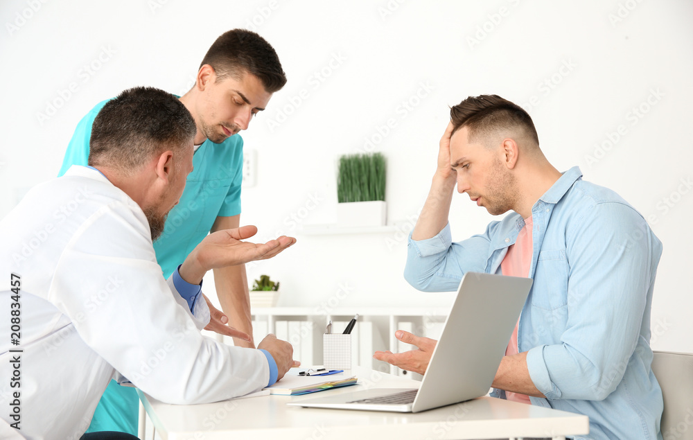 Obraz premium Male doctor and his assistant working with patient in clinic. Cardiology consultation