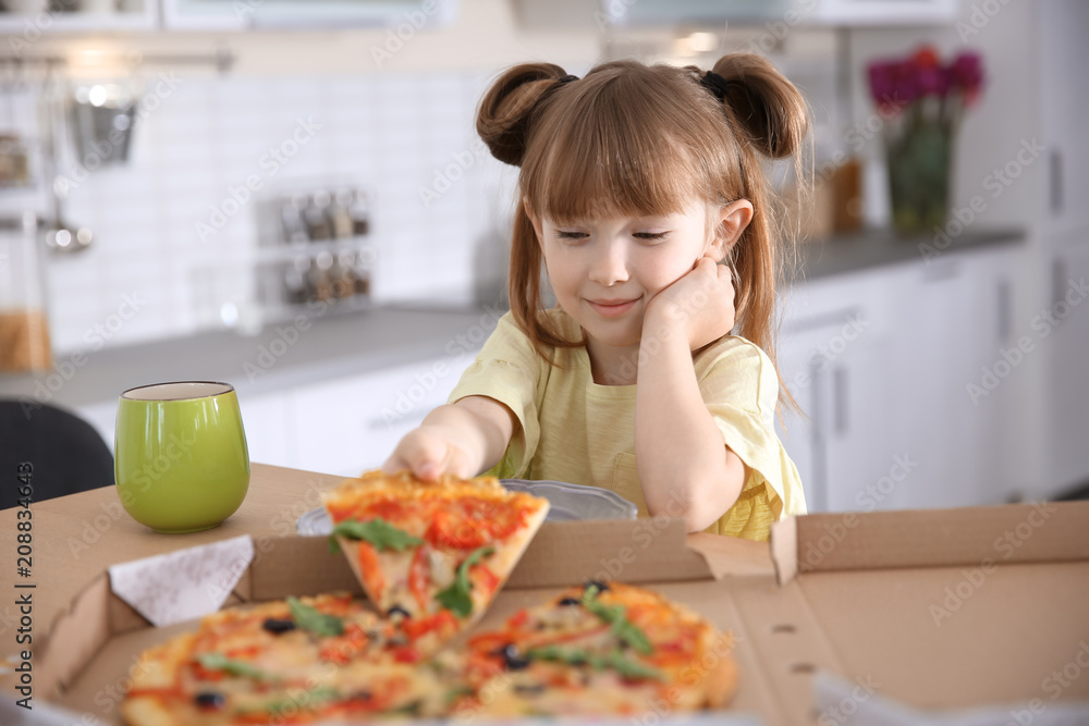 Cute little girl eating tasty pizza at home